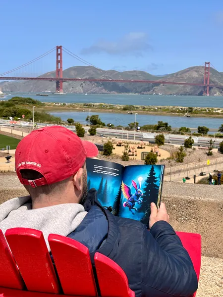 Leyendo el libro frente al Golden Gate en un banco rojo