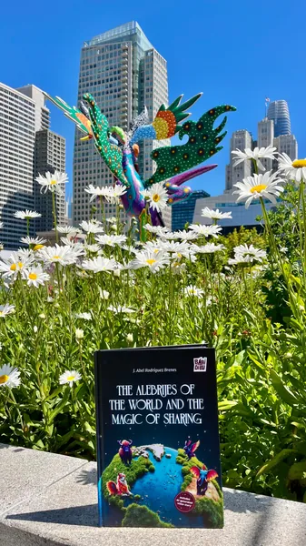 El libro entre margaritas con un alebrije y la ciudad de San Francisco